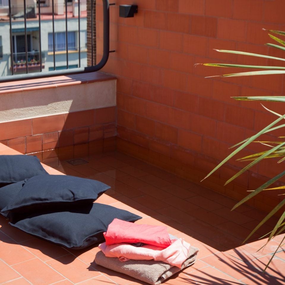 Luxurious rooftop terrace of modern boutique hotel overlooking Barcelona's skyline, with sleek lounge chairs and panoramic Mediterranean views