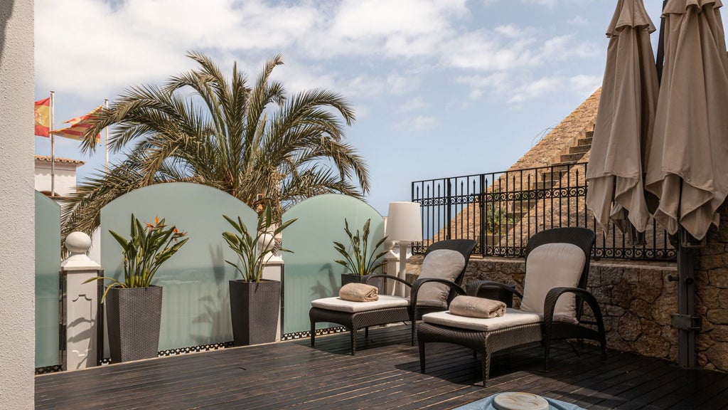 Luxurious balcony view of Hotel Mirador de Dalt Vila, overlooking historic Ibiza old town with stone walls and Mediterranean sunset backdrop