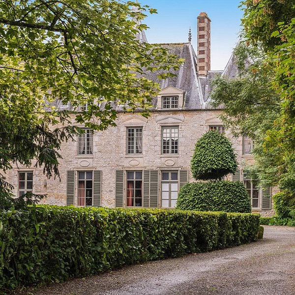 Elegant 18th-century French château with ornate architecture, manicured gardens, and soft golden sunlight highlighting its timeless stone facade and refined windows