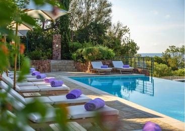 Luxurious seaside hotel with Côte d'Azur blue waters, elegant white facade, lush Mediterranean gardens, and stunning coastal landscape in southern France