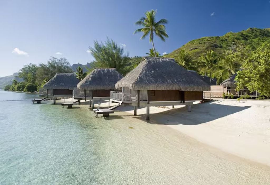 Luxurious overwater bungalow with private deck, clear turquoise lagoon views, and plush king bed in tropical Moorea setting