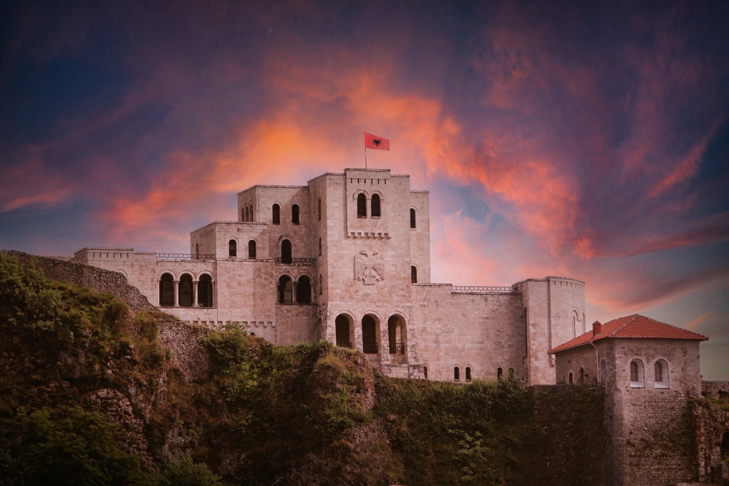 Panoramic view of scenic Kruja Castle perched on rocky mountainside with Dajti Mountain range backdrop, traditional Albanian landscape with lush green valleys