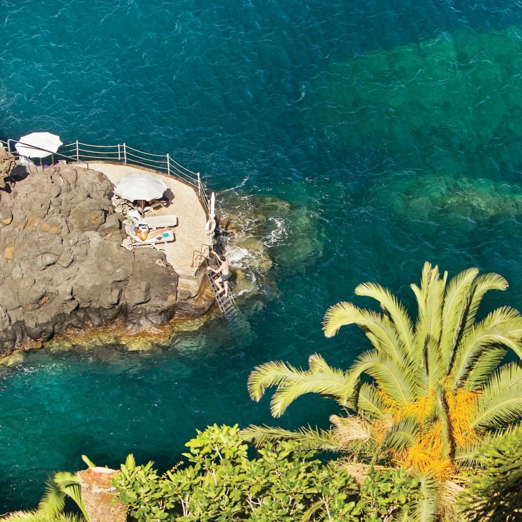 Historic pink luxury hotel perched on Madeira cliffs, featuring elegant terraces, lush gardens and panoramic Atlantic Ocean views