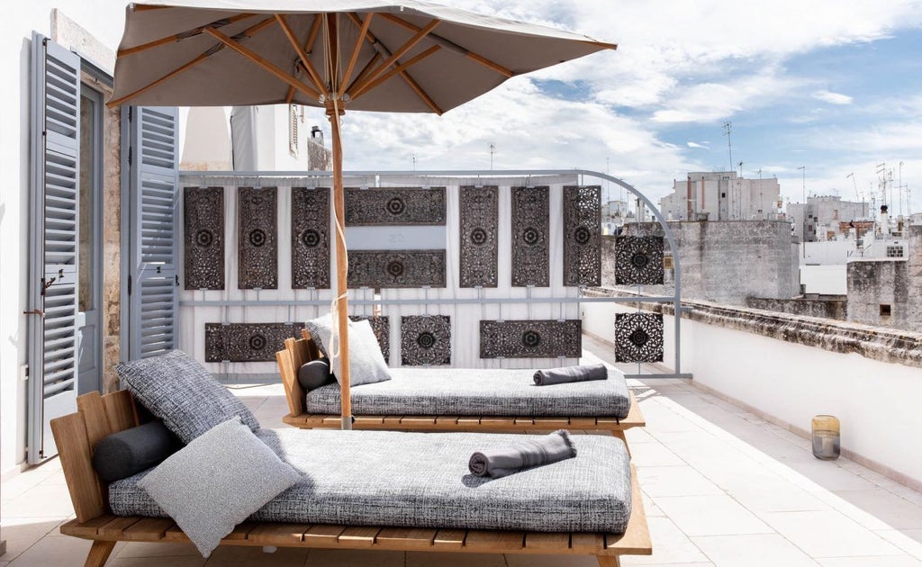 Luxurious red brick facade of Boutique Hotel in Ostuni, Italy, with elegant architectural details and warm Mediterranean sunlight cascading over ornate balconies