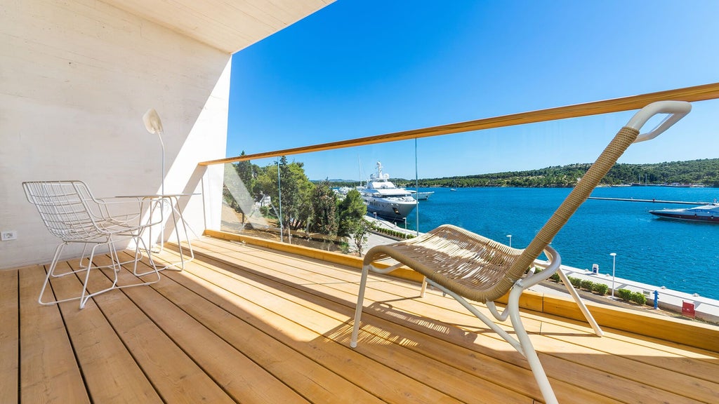 Spacious deluxe hotel room with modern minimalist design, panoramic sea view, elegant contemporary furnishings, and soft neutral color palette in Šibenik, Croatia