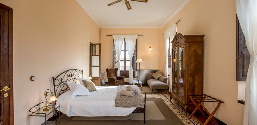 Luxurious stone-walled Spanish suite in Cortijo del Marqués, featuring rustic wooden beams, elegant four-poster bed, and warm ambient lighting