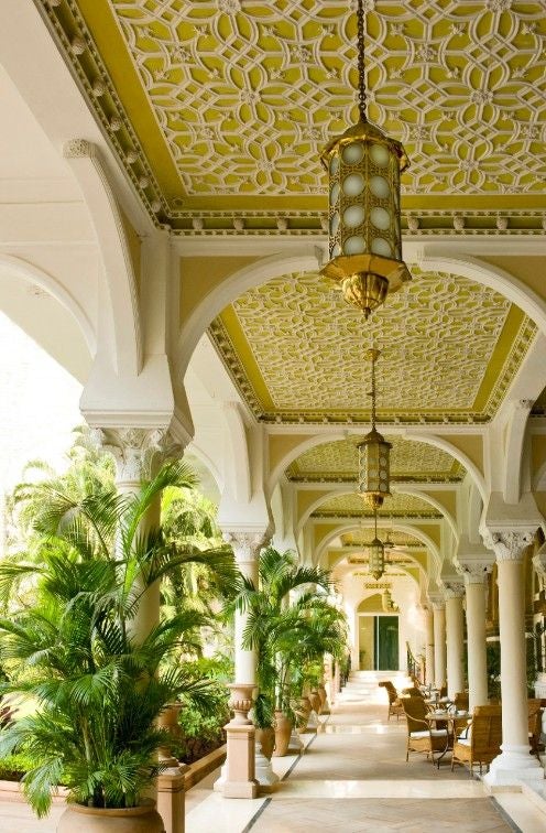 Historic Taj Mahal Palace Hotel in Mumbai with elegant colonial architecture, ornate domes, palm trees, and luxurious entrance facade