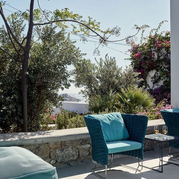 Luxurious white minimalist bedroom with panoramic Aegean Sea view, featuring clean lines, modern white furniture, and expansive glass doors at Myconian Ambassador Hotel