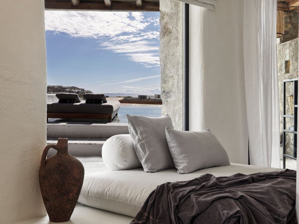 Modern minimalist boutique hotel in Mykonos with whitewashed walls, private infinity pool overlooking Aegean Sea, luxury sunbeds and natural textures