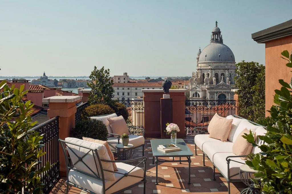 Elegant Venetian hotel with ornate marble balconies overlooking Grand Canal, featuring terrace dining and classic Italian architecture