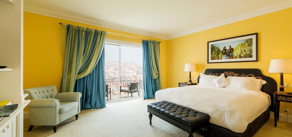 Elegant executive room with plush king bed, private balcony overlooking Porto's wine cellars, and marble bathroom with soaking tub