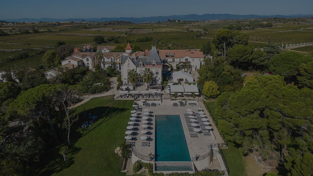 Luxurious French château hotel nestled in scenic vineyards, featuring elegant stone architecture, manicured gardens, and golden sunset lighting.