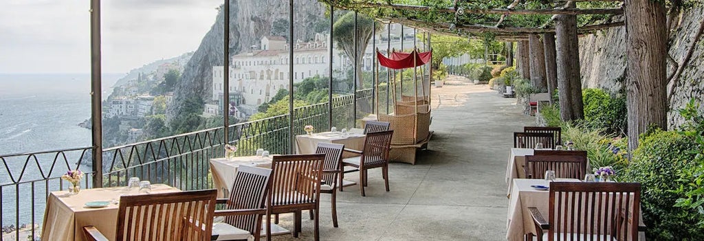 Historic cliffside Italian luxury hotel with whitewashed walls, stone arches and sweeping sea views over the Amalfi Coast's azure waters