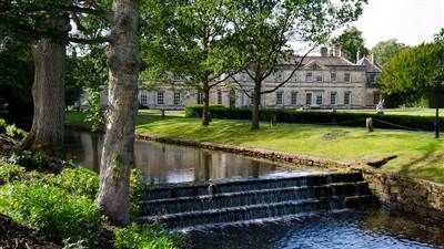 Elegant three-story Georgian mansion with manicured gardens, showcasing refined luxury of a historic UK hotel set against lush green landscape