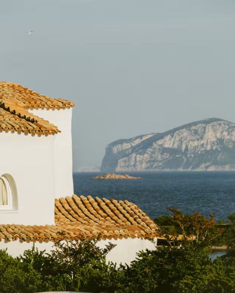 Mediterranean-style luxury hotel with white stucco walls, arched windows and private terraces overlooking turquoise Costa Smeralda waters