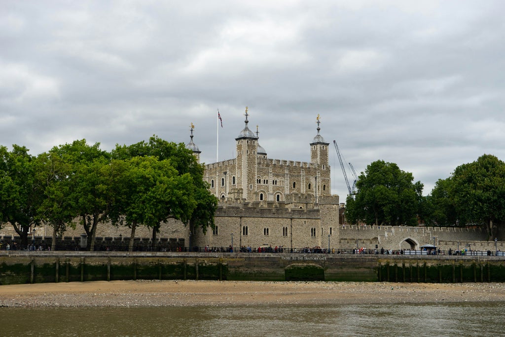 Tower of London castle view at sunrise, featuring iconic medieval architecture with ornate stone walls and turrets against a golden sky