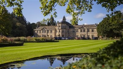 Luxurious three-story Scenset Hall hotel with elegant stone facade, manicured gardens, and grand architectural design in the United Kingdom countryside