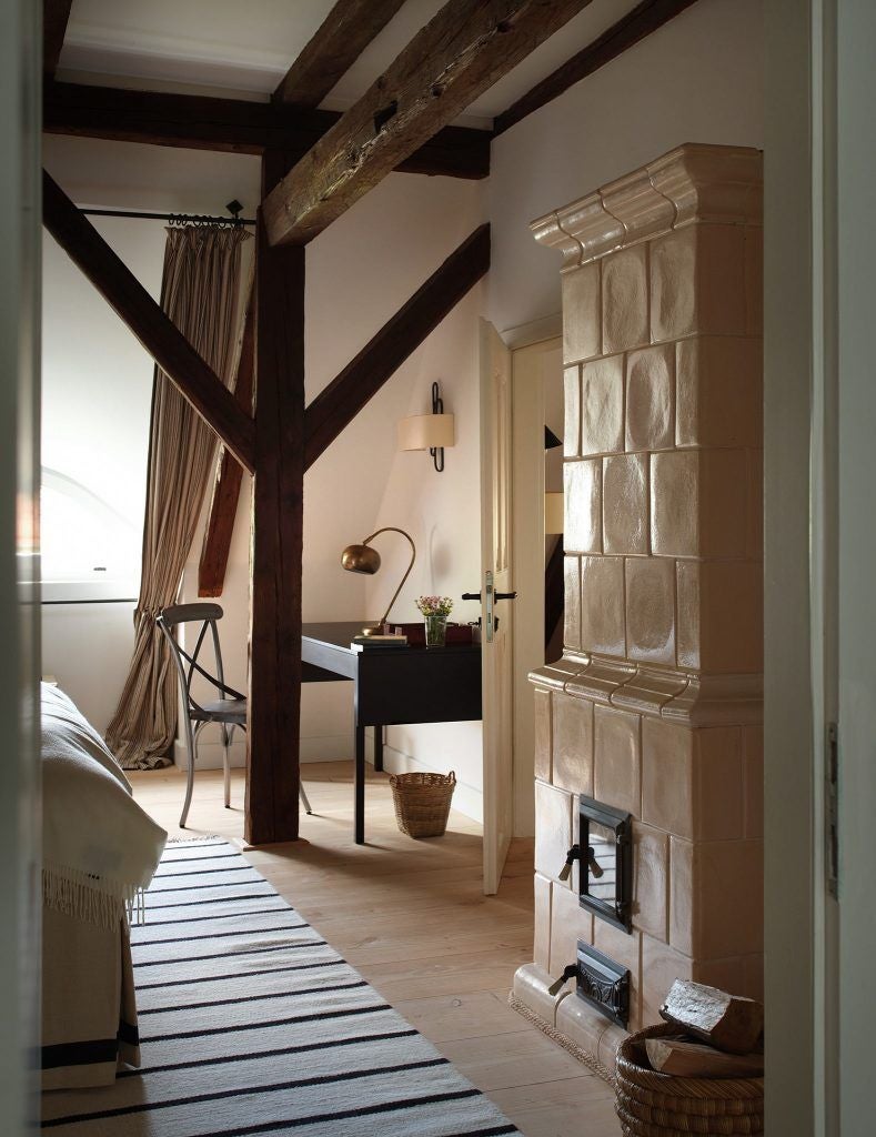 Rustic wooden interior of renovated caretaker's house at Bethlen Estates, featuring exposed beams, antique furnishings, and warm ambient lighting in Transylvanian countryside