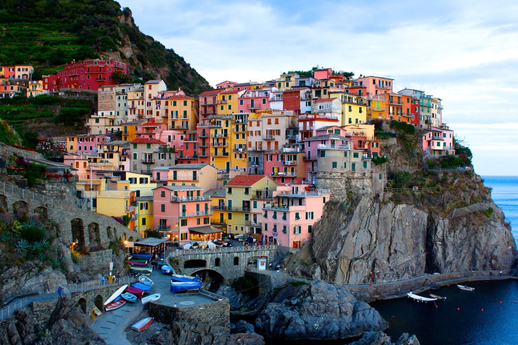 Vibrant pastel-colored houses perched on steep cliffs along the Mediterranean coast of Cinque Terre village at golden sunset