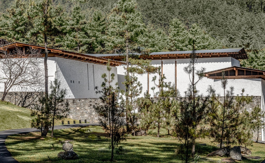 Luxurious mountain lodge with traditional Bhutanese architecture nestled in pine forests, featuring stone walls and expansive windows