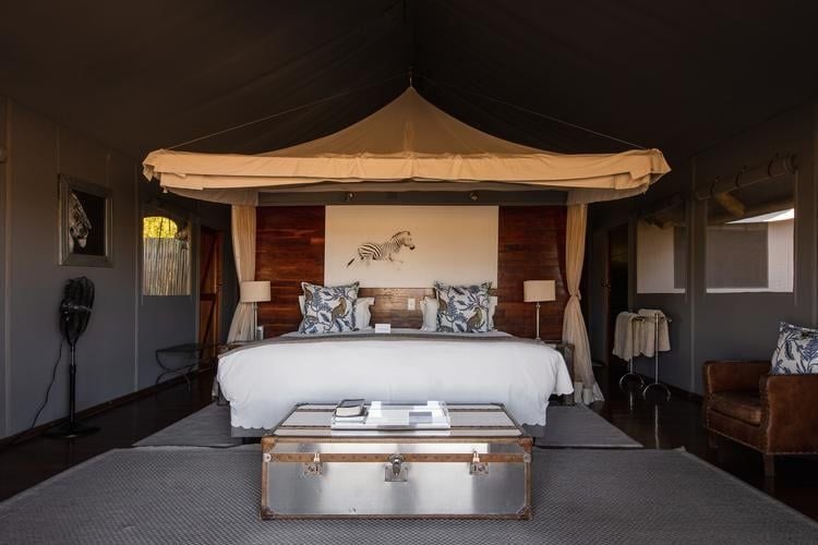 Luxury safari tent with wooden deck overlooking Botswana's wilderness, featuring elegant furnishings and sweeping views of the scenic landscape at Chitabe Lediba Camp.