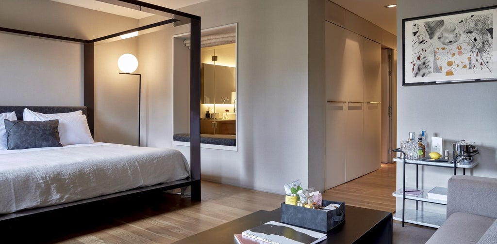 Luxurious modern hotel suite at Sir Victor in Barcelona, featuring minimalist design, elegant neutral tones, and floor-to-ceiling windows overlooking urban landscape