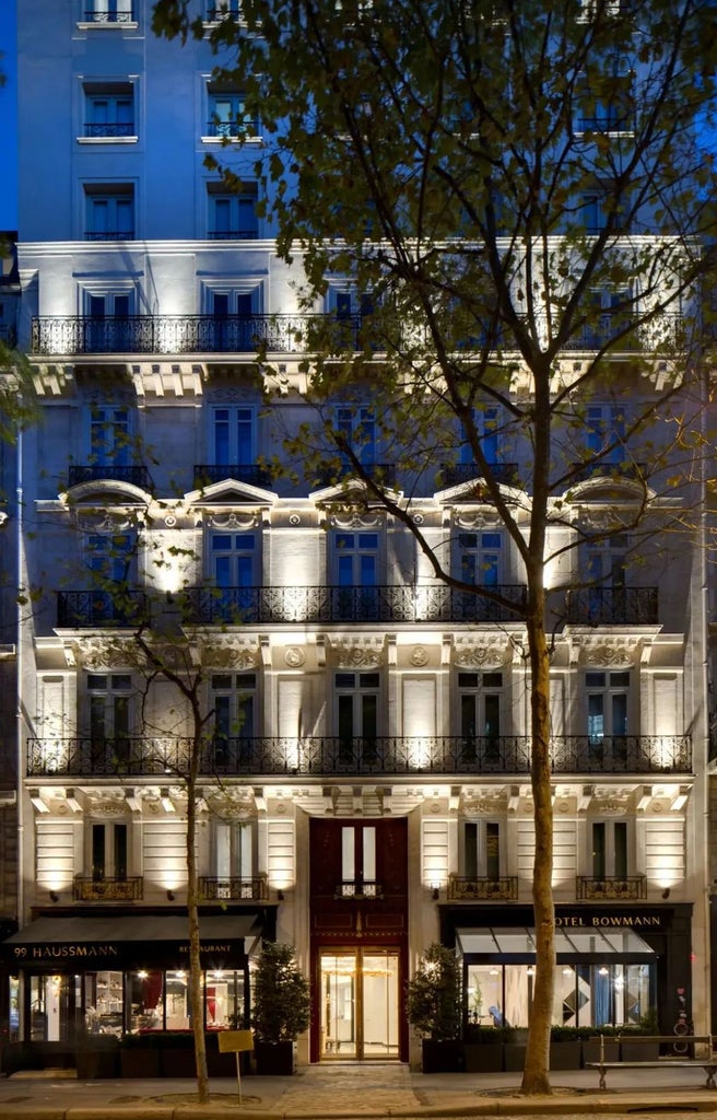 Elegant Parisian hotel facade with ornate Haussmann-style architecture, classic iron balconies and charming dormer windows at sunset