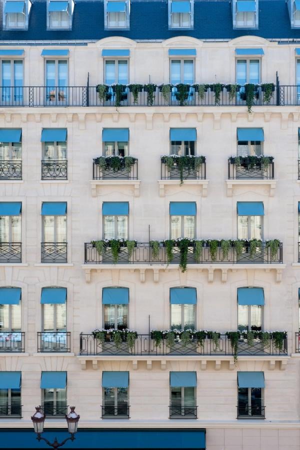 Elegant marble entranceway of Hotel Nolinski Paris featuring gold art deco details, mirrored walls and a grand chandelier in warm lighting