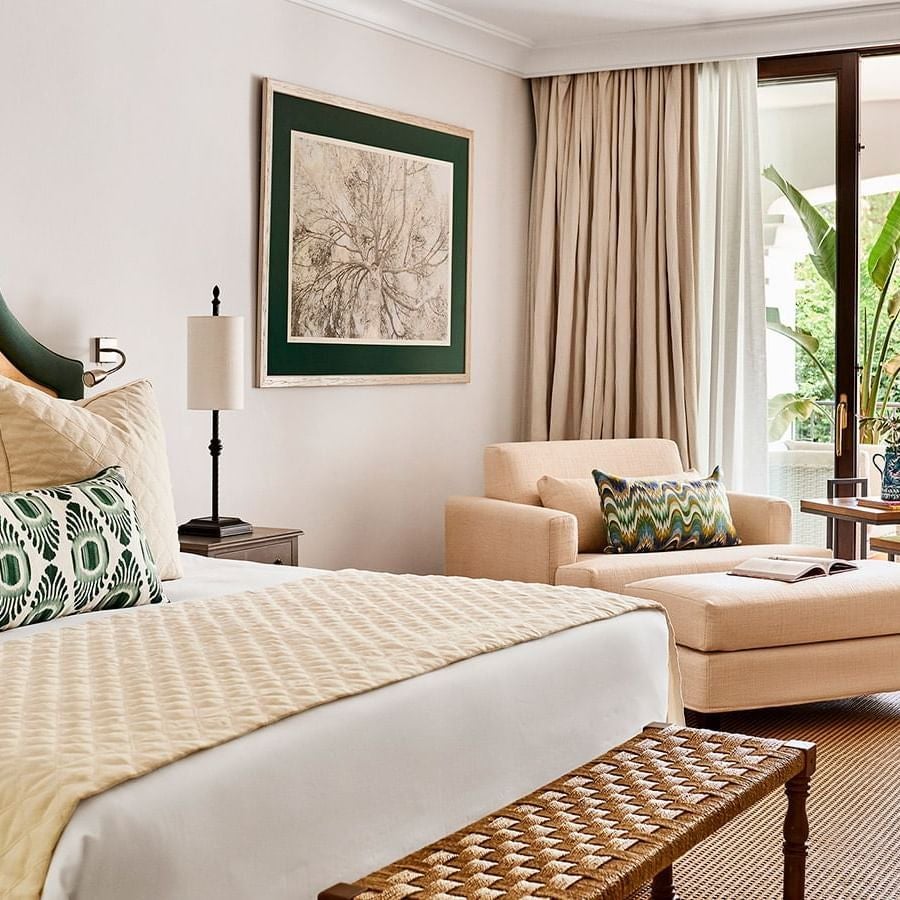 Elegant deluxe hotel room with Mediterranean coastal decor, white linens, ocean-view balcony, and soft natural light at coastal Spanish resort