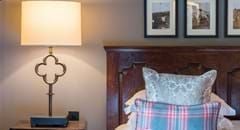 Elegant cottage-style hotel room with plush white bedding, vintage wood furnishings, and soft neutral tones at The Lygon Arms luxury boutique hotel