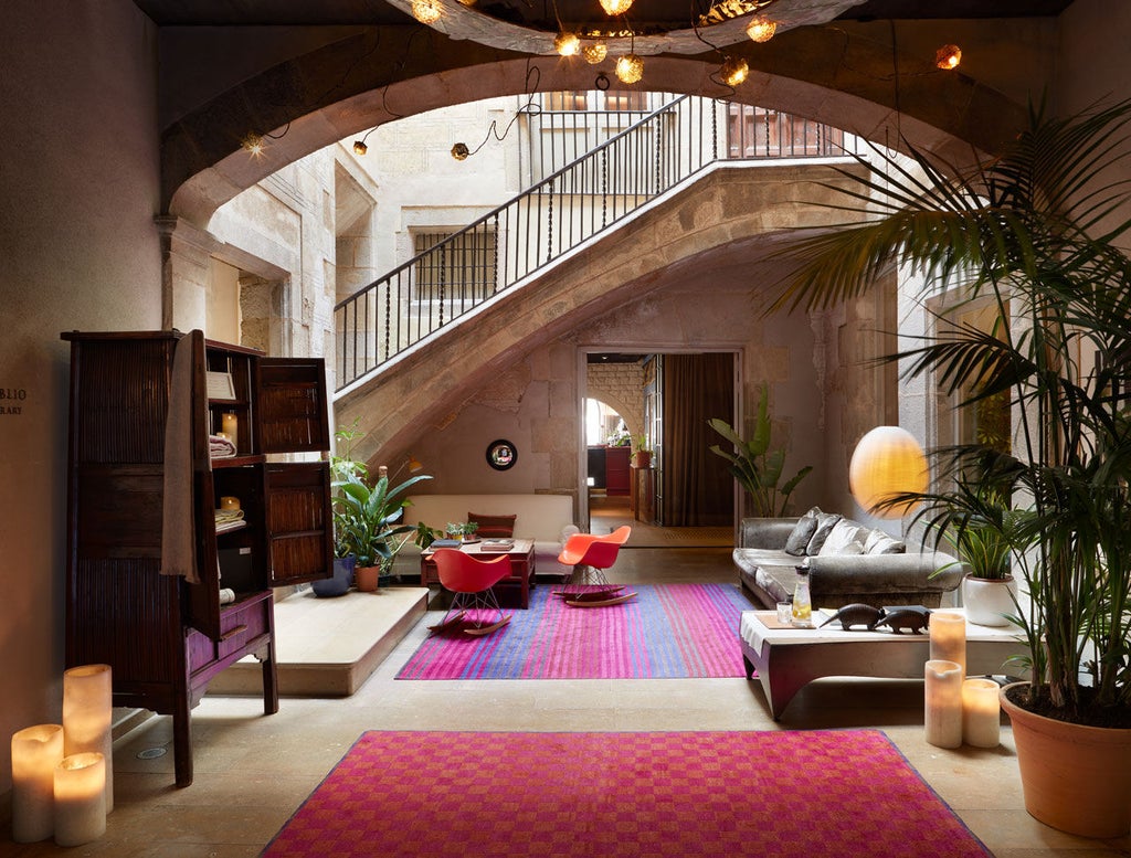 Historic luxury hotel with warm stone facade, arched windows, and ornate iron balconies nestled in Barcelona's Gothic Quarter at dusk