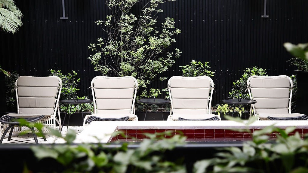 Elegant boutique hotel facade with white exterior, lush garden, wrought-iron balconies, and traditional Portuguese architectural details in Lisbon.