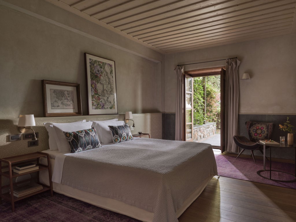 Elegant master suite with vaulted stone ceilings, king bed with white linens, vintage decor and natural light from arched windows