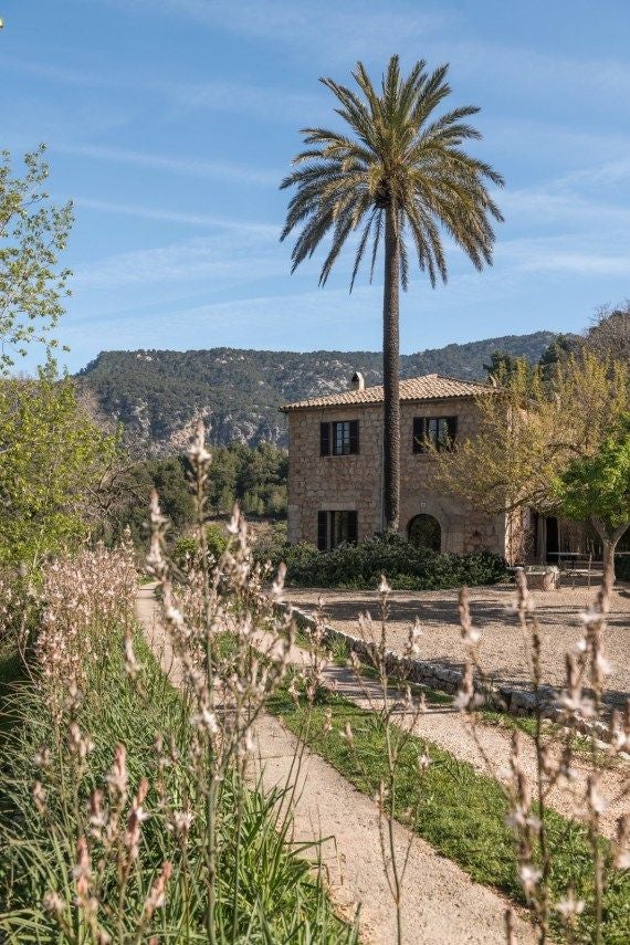 Luxurious stone terrace of Mirabó hotel overlooking lush Valldemossa landscape, with elegant outdoor seating and vibrant Mediterranean greenery