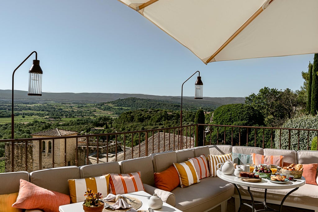 Elegant stone hotel nestled in French countryside with terracotta roofs, manicured gardens and panoramic views of Provence region