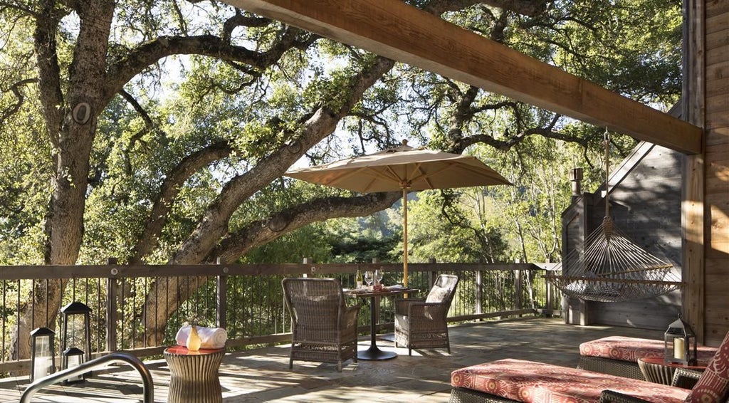 Luxurious rustic cottage interior with natural wood accents, plush bedding, and panoramic window overlooking scenic Big Sur landscape at coastal California retreat.