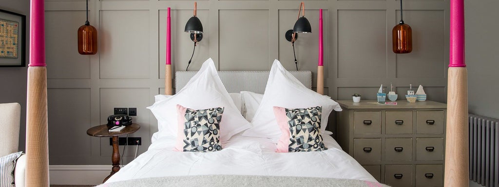 Elegantly designed luxury hotel room at The Swan in Southwold, featuring plush white bedding, coastal-inspired decor, and warm wooden furnishings with soft natural light