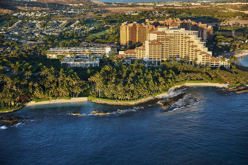 Oceanfront luxury hotel with multi-tiered infinity pools, swaying palm trees and private cabanas overlooking pristine Hawaiian beach