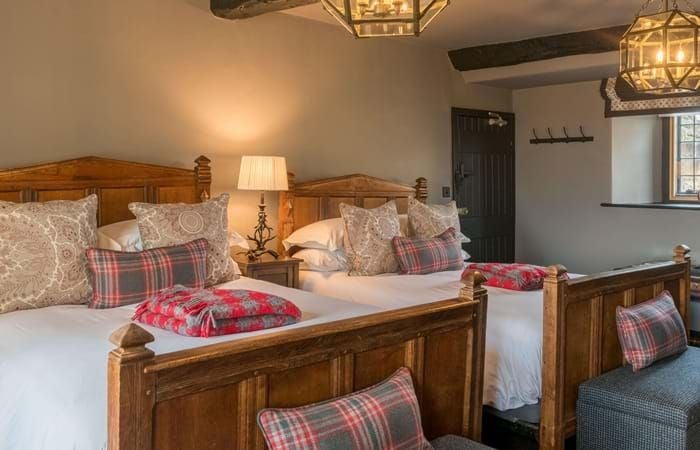 Elegant classic hotel room with plush white bedding, wooden furnishings, and soft neutral tones, showcasing refined British hospitality at The Lygon Arms