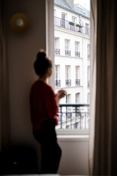 Elegant Parisian boutique hotel with soft cream facade, ornate balconies, and classic French architectural details against a warm afternoon light