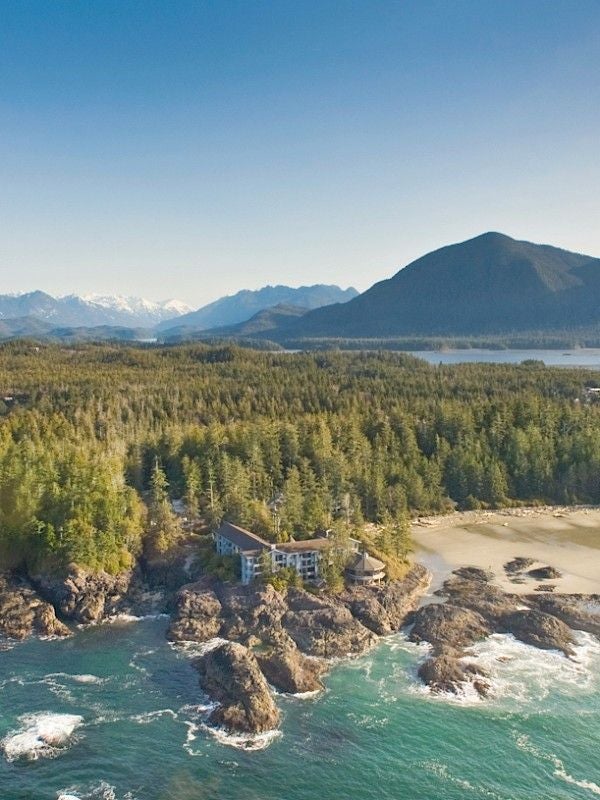 Luxury oceanfront lodge perched on rugged cliffs of Vancouver Island, featuring cedar architecture and panoramic Pacific views at sunset