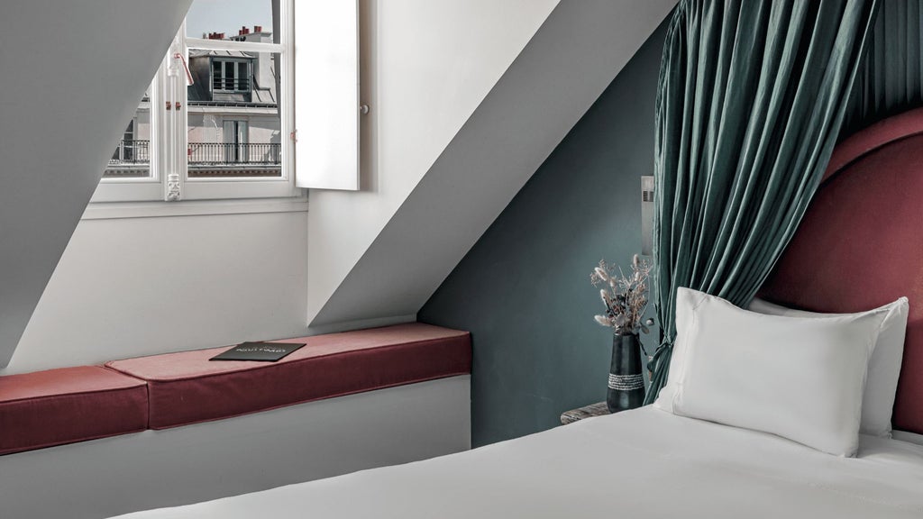 Elegant Parisian hotel room with ornate chandelier, plush white linens, antique furnishings, and large windows overlooking historic boulevards at dusk