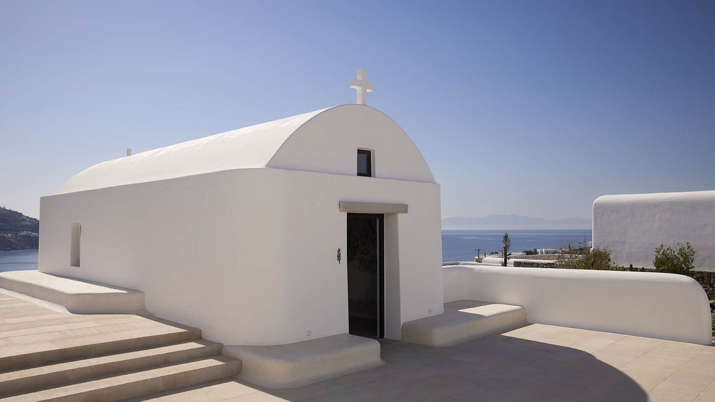 Whitewashed luxury villa with private infinity pool overlooking Aegean Sea at sunset, featuring minimalist Cycladic architecture