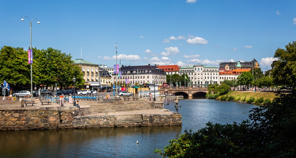 Elegant canal cruise boat gliding through Gothenburg's historic waterways, passing colorful architecture and under charming bridges at golden hour