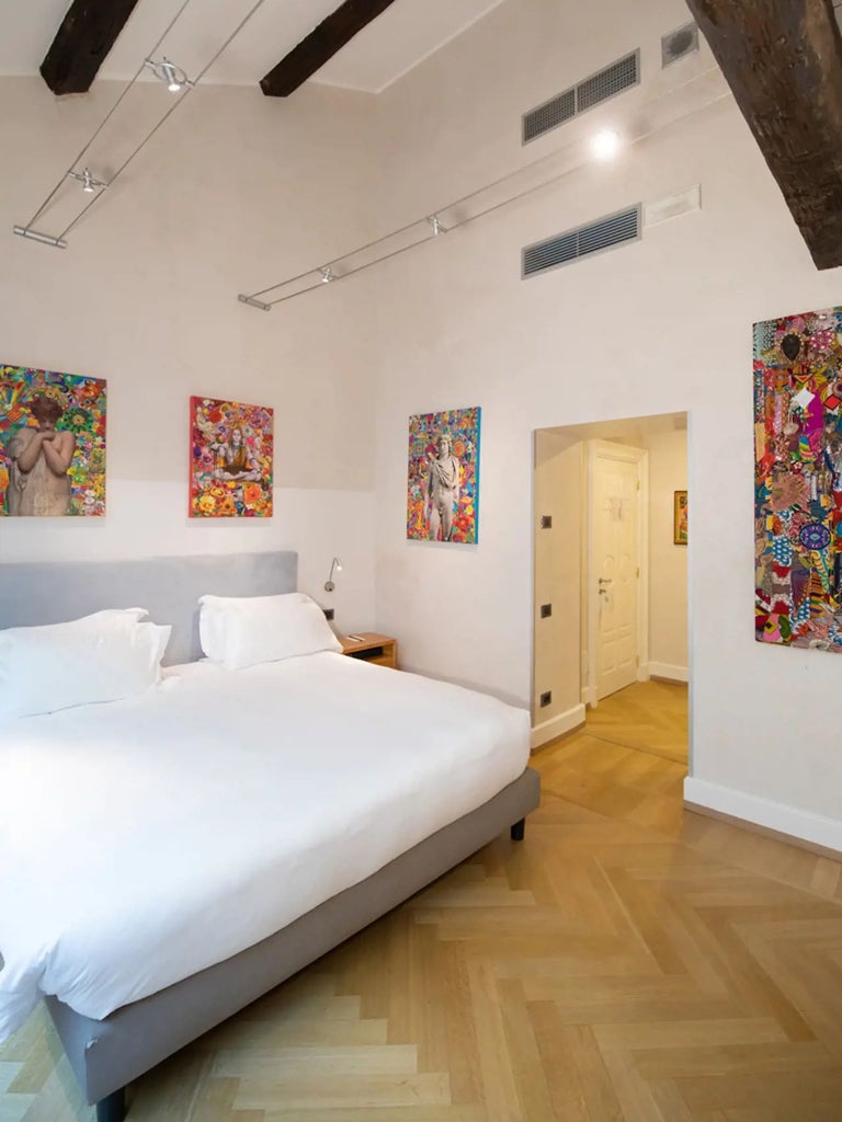 Luxurious deluxe hotel room with modern Italian design, floor-to-ceiling windows, minimalist furnishings, and artistic city view in Milan's Galleria Vik