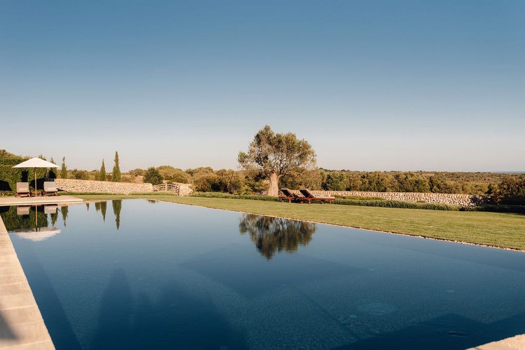 Luxurious whitewashed Spanish farmhouse hotel nestled in Menorca's countryside, featuring stone walls, elegant terrace, and serene Mediterranean landscape