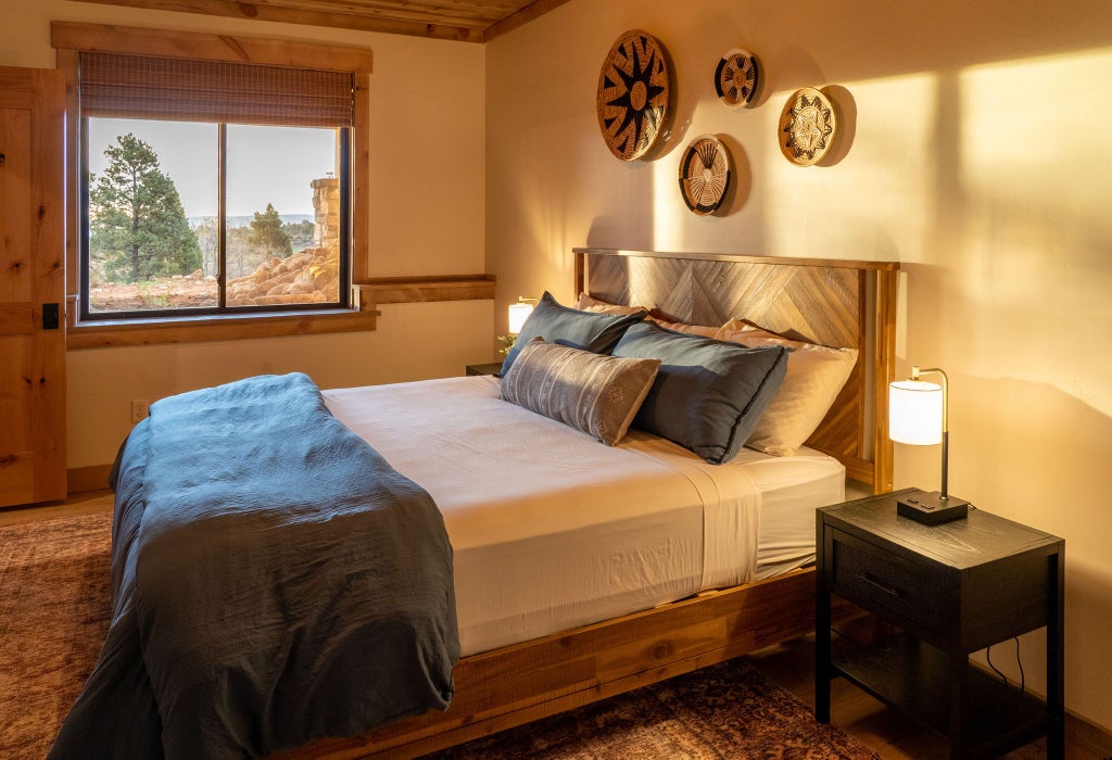 Spacious rustic lodge room with wooden furnishings, plush bedding, and panoramic mountain views in a serene United States wilderness setting.