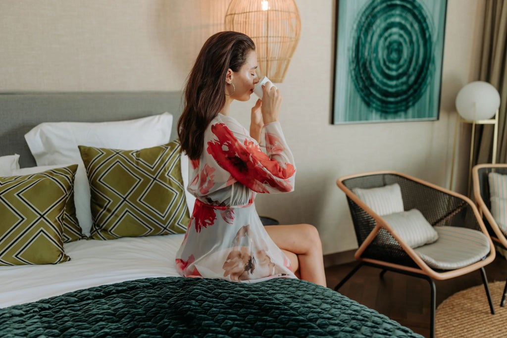 Elegant boho-chic superior hotel room with warm terracotta tones, natural textiles, rattan furniture, and soft ambient lighting in a Spanish-inspired design