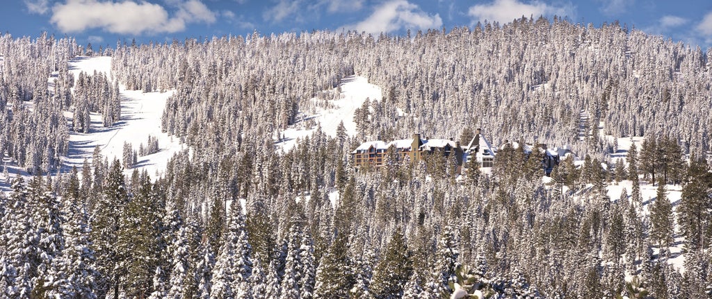 Luxury mountain resort with snow-capped peaks, stone and timber facade, grand entrance terrace, and panoramic Lake Tahoe views