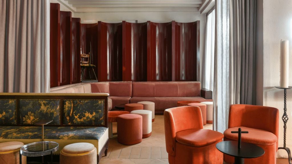 Opulent boutique hotel lobby in Paris with rich velvet seating, dramatic mood lighting, and moody contemporary art against dark, textured walls.